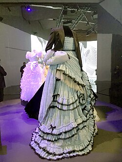 A pale blue dress with frills, on display at a museum