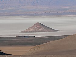 "Cono de Arita" at the dry lake Salar de Arizaro on the Atacama Plateau, in northwestern Argentina. The cone itself is a volcanic edifice, representing complex interaction of intrusive igneous rocks with the surrounding salt.[10]