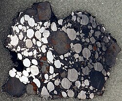 Gujba meteorite, a bencubbinite found in Nigeria. Polished slice, 4.6 × 3.8 cm. Note the nickel-iron chondrules, which have been age-dated to 4.5627 billion years.