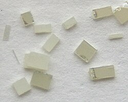Synthetic single crystals of TiO2, c. 2–3 mm in size, cut from a larger plate
