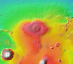 MOLA topographic map of Alba Mons and surroundings. The main edifice appears in colors of red to orange; the surrounding apron is in shades of yellow-orange to green. The relief is greatest to the north because the volcano straddles the dichotomy boundary. Elevated terrain of Ceraunius Fossae, which underlies part of the volcano, extends southward like a handle.