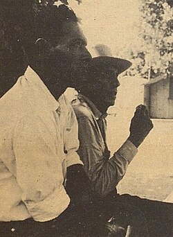 Two farm workers in the Linnell Labor Camp discuss conditions with SNCC field secretary.