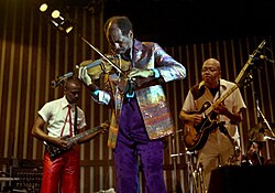 Coleman playing the violin with Prime Time in 1978, flanked by guitarists Charlie Ellerbee (left) and Bern Nix (right)