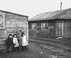 Native Alaskan children standing in front of their homes.