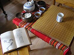 A contemporary Japanese porcelain goblet (in the middle of the Go board) and a Chinese teapot and its cups (on the side)