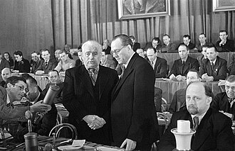 Otto Grotewohl (right) and Wilhelm Pieck (left) seal the unification of the SPD and KPD with a symbolic handshake. Walter Ulbricht is seated in the foreground to the right of Grotewohl. Photograph by Avraham Pisarek, 21 April 1946.