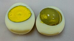 An overcooked hard-boiled egg, showing the distinctive green coating on the yolk caused by the presence of iron(II) sulfide