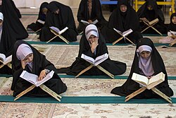 Muslim girls studying the Quran placed atop folding lecterns (rehal) during Ramadan in Qom, Iran