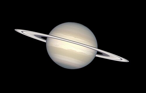 The ring orbiting Saturn consists mostly of chunks of ice and dust. The small dark spot on Saturn is the shadow from Saturn's moon Enceladus.