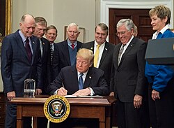 President Trump signs Space Policy Directive 1 on December 11, 2017, with astronauts Harrison Schmitt, Buzz Aldrin, Peggy Whitson, and Christina Koch looking on.