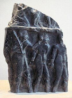Prisoners escorted by a soldier, on a victory stele of Sargon of Akkad, c. 2300 BC.[42] Probably from the end of Sargon's reign.[43] The hairstyle of the prisoners (curly hair on top and short hair on the sides) is characteristic of Sumerians, as also seen on the Standard of Ur.[44] Louvre Museum.