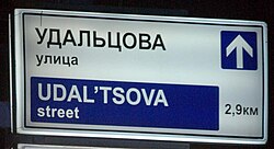 A street sign in Russia with the name of a street shown in Cyrillic and Latin characters