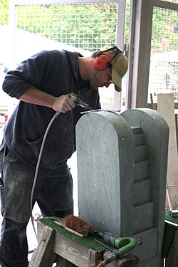 Stonemason dressing stone on a fountain with pneumatic tools