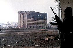 A Chechen fighter near the burned-out ruins of the Presidential Palace in Grozny, January 1995