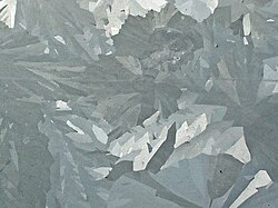 Merged elongated crystals of various shades of gray.