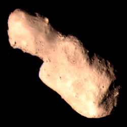 Photograph of an elongated, rocky asteroid, on the black background of space, taken by a space probe.