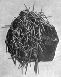 Lodestone, a natural magnet, attracting iron nails. Ancient humans discovered the property of magnetism from lodestone.