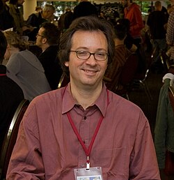 Photo of a man seated and wearing glasses
