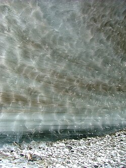 A cross-section through a glacier. The base of the glacier is more transparent as a result of melting.