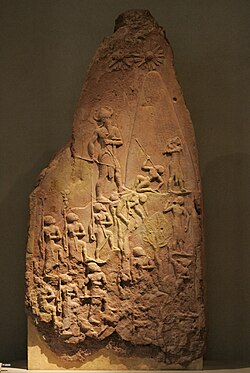 Victory Stele of Naram-Sin, celebrating victory against the Lullubi from Zagros 2260 BC. He is wearing a horned helmet, a symbol of divinity, and is also portrayed in a larger scale in comparison to others to emphasize his superiority.[69] Brought back from Sippar to Susa as war prize in the 12th century BC.