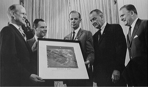 Jack N. James (center), JPL's Mariner 4 Project Manager, with a group in the White House presenting the spacecraft's famous picture Number 11 of Mars to US President Lyndon B. Johnson (center right) in July 1965