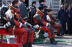 U.S. Navy divers in dry suits prepare to dive