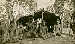 Indigenous Australian boys and men in front of a bush shelter, Groote Eylandt, circa 1933