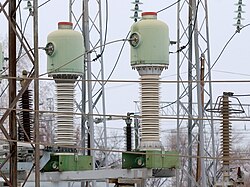 Minaret-like electrical devices with wires around them, thicker at the bottom