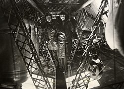 Lady Drummond-Hay standing in front of an unnamed man between the fuel tanks in the lower gangway of the Graf Zeppelin during the 1929 world tour.