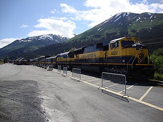 A northbound Alaska Railroad passenger train idles at the Seward depot on June 30, 2010. Race Point on Mount Marathon is the high point on the right-hand side.