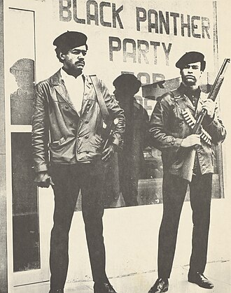 Black Panther Party founders Bobby Seale and Huey P. Newton standing in the street, armed with a Colt .45 and a shotgun