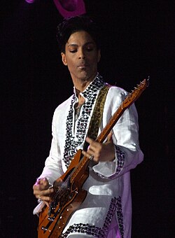 Prince performing on stage with a guitar