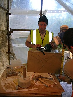 A stonemason at Eglinton Tournament Bridge with a selection of tools of the trade