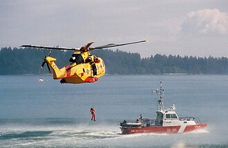 A Canadian Forces AgustaWestland CH-149 Cormorant helicopter hoists a man from a Canadian Coast Guard ship