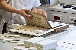 A book conservator examining pages of a bound volume