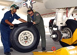 Two mechanics replacing a main landing gear wheel on a Lockheed P-3 Orion