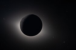 The crew photographed a solar eclipse, with the Moon blocking out the Sun. Earthshine illuminates parts of the Moon and either or both the solar corona and the zodiacal light are visible as a spiking glow around the Moon.[108]