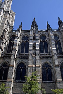 Exterior of the nave. Two of the double bays can be seen here, with four columns of windows in total. At center is a large arched buttress, while smaller buttresses to the left and right separate each set of double bays.