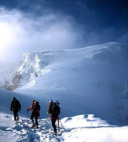 Mountaineers proceed across snow fields on South Tyrol; other climbers are visible further up the slopes.