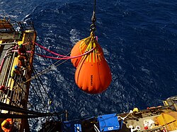 Water-filled crane test bags suspended over the sea during offshore crane load testing operations on a vessel.