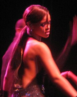 Rihanna, in her late teens, facing the other way of the camera under a red light