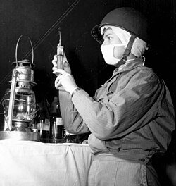 U.S. Army nurse wearing a helmet and fatigue uniform.
