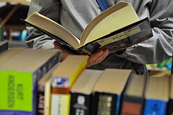 A person reading a book, in a second-hand store.