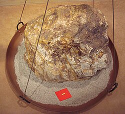 Relative sizes of an 860 kg (1,900 lb) block of gold ore and the 30 g (0.96 ozt) of gold that can be extracted from it, Toi gold mine, Japan.