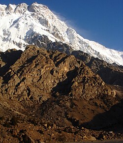 View from Latbo village. For a sense of scale, notice a four-man yellow tent, dwarfed by the peak, near the bottom right. Just above the tent is a large white building.