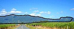 The Djabugay language group's mythical being, Damarri, transformed into a mountain range, is seen lying on his back above the Barron River Gorge, looking upwards to the skies, within north-east Australia's wet tropical forested landscape