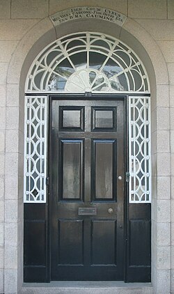 Door of 9 Pier Road, Saint Helier, Jersey – house given to La Société Jersiaise for use as museum (now part of the Jersey Museum). Motto over door reads: Fier coum Cyrus, mes viers garçons, j'vos ouvre l'us, l'us d'ma caumine (Proud as Cyrus, my old boys, I open to you the door, the door of my cottage)