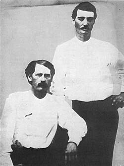 Deputies Bat Masterson (standing) and Wyatt Earp in Dodge City, 1876. The scroll on Earp's chest is a cloth pin-on badge