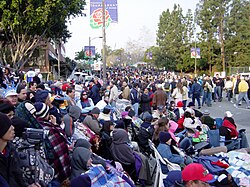 Spectators gather before the 2004 Rose Parade: some pay for seats in stands; others spend the night to "reserve" a free spot on the sidewalks.