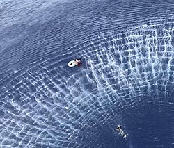 A US Navy rescue swimmer swims toward a stranded boat near Guam in 2019